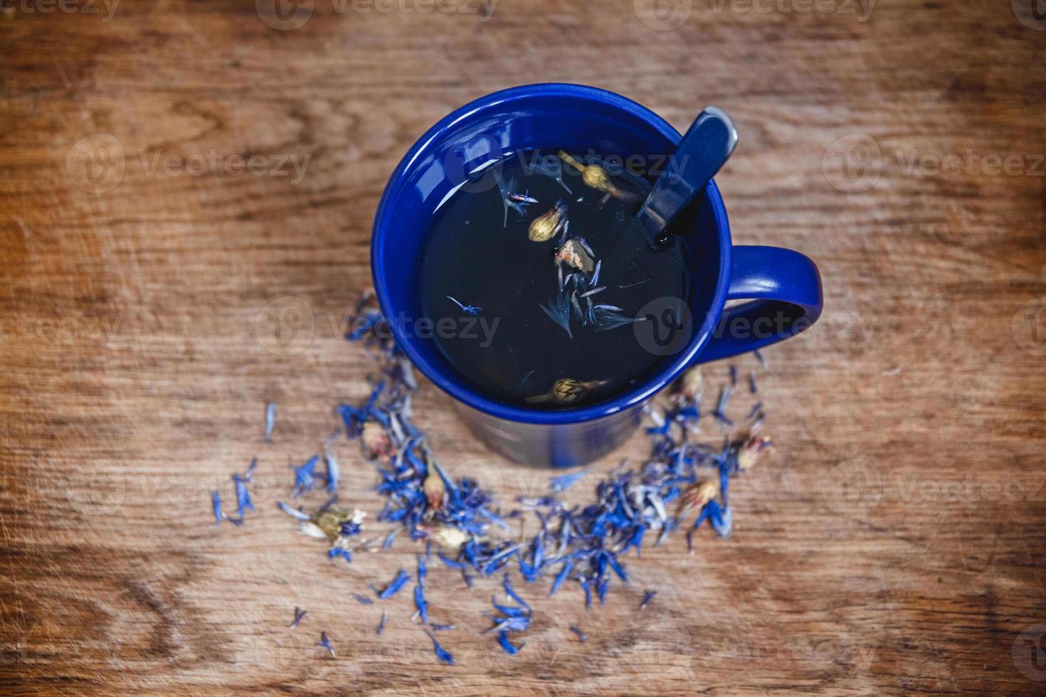 Blue cup and spoon with flowered black tea on a wooden background photo