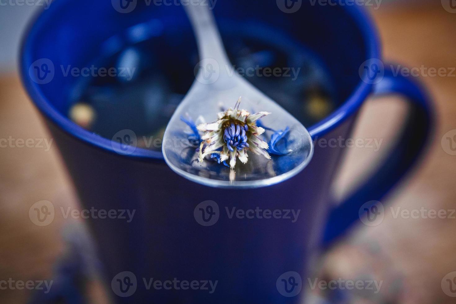 Blue cup and spoon with flowered black tea on a wooden background photo