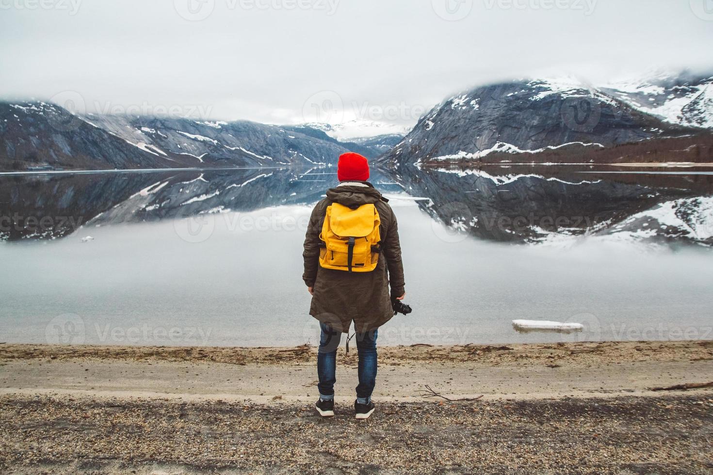 man standing on background of mountains and lake makes a photo