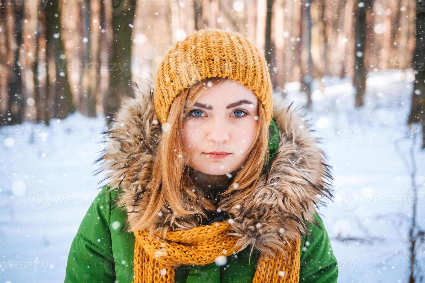 Mujer en ropa de invierno sobre un fondo de bosque cubierto de nieve foto