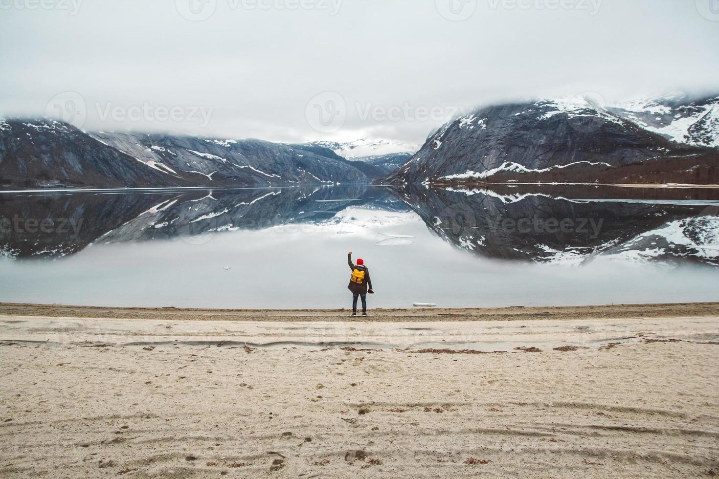 man standing on background of mountains and lake makes a photo