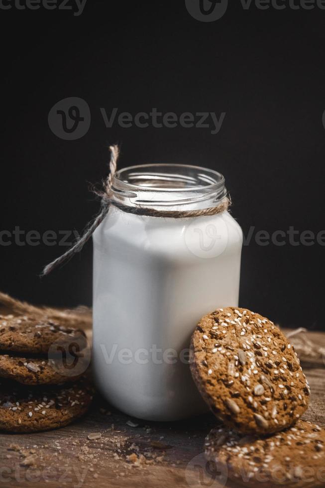 galletas de cereales con una jarra de leche sobre un fondo de madera. foto