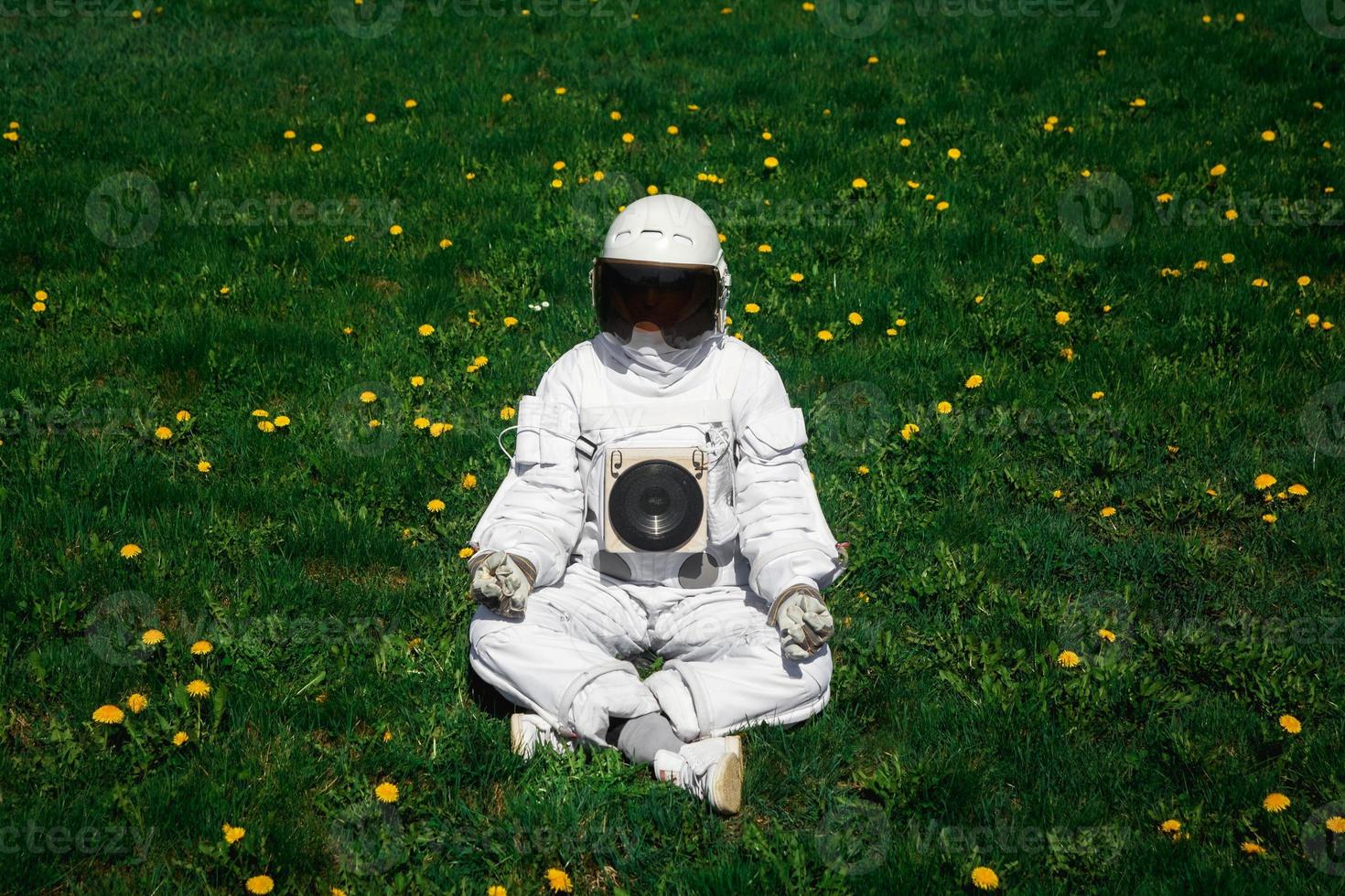 Futuristic astronaut in a helmet sits on a green lawn among flowers photo