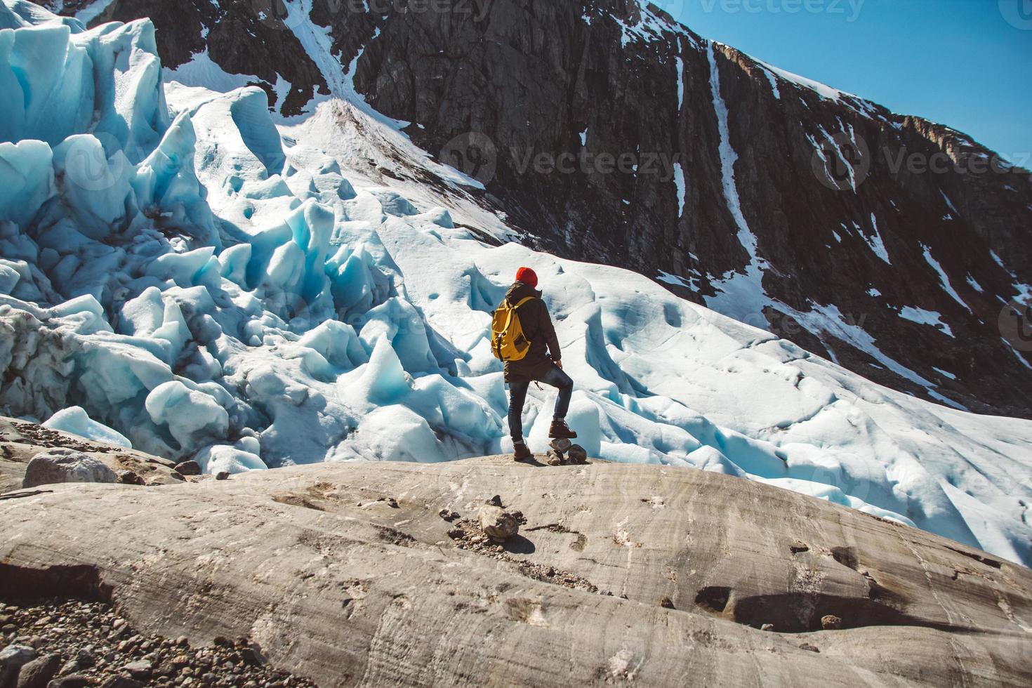 Hombre viajero de pie sobre una roca en el fondo de un glaciar foto