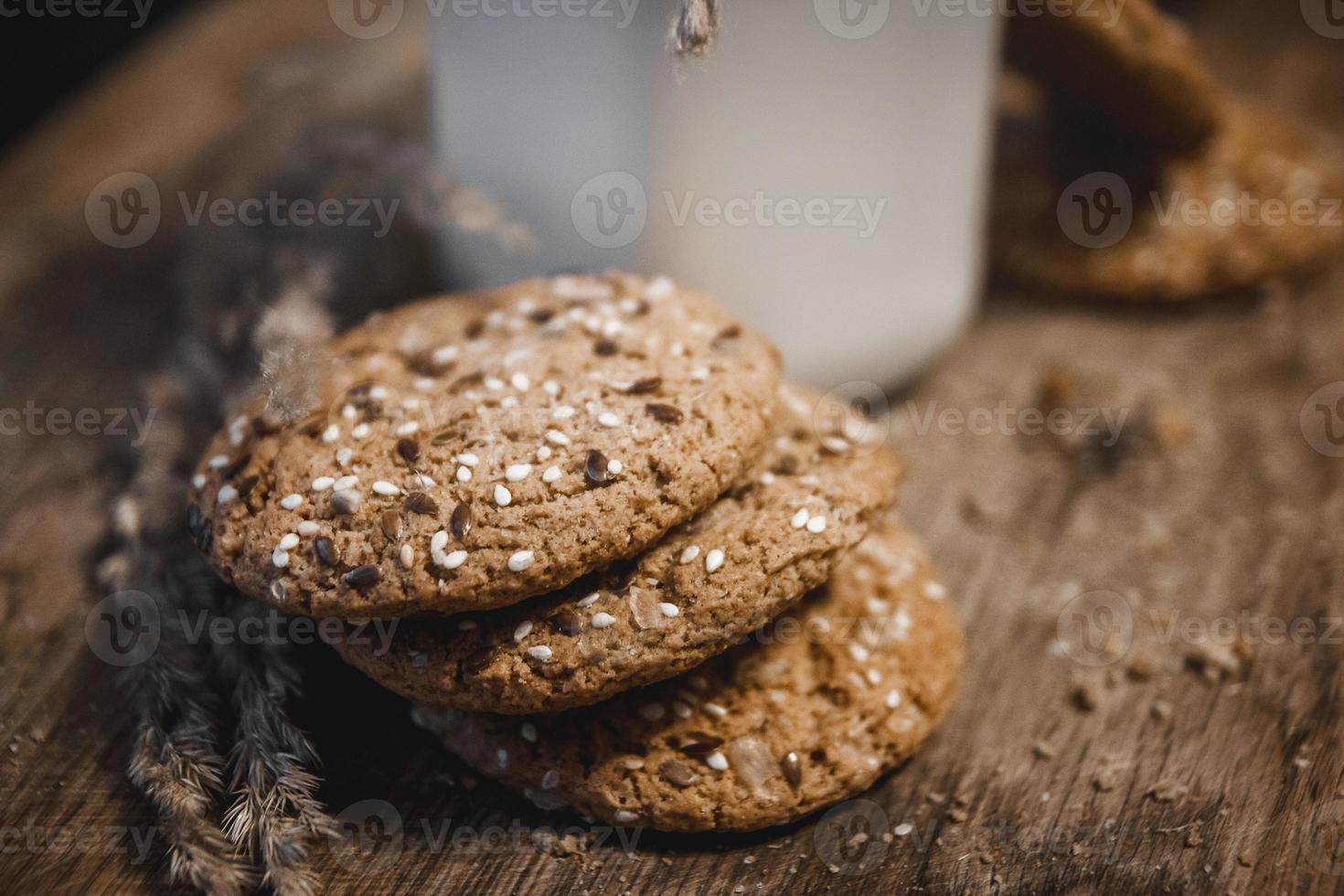 Cereal cookies with a jug of milk on a wooden background. photo