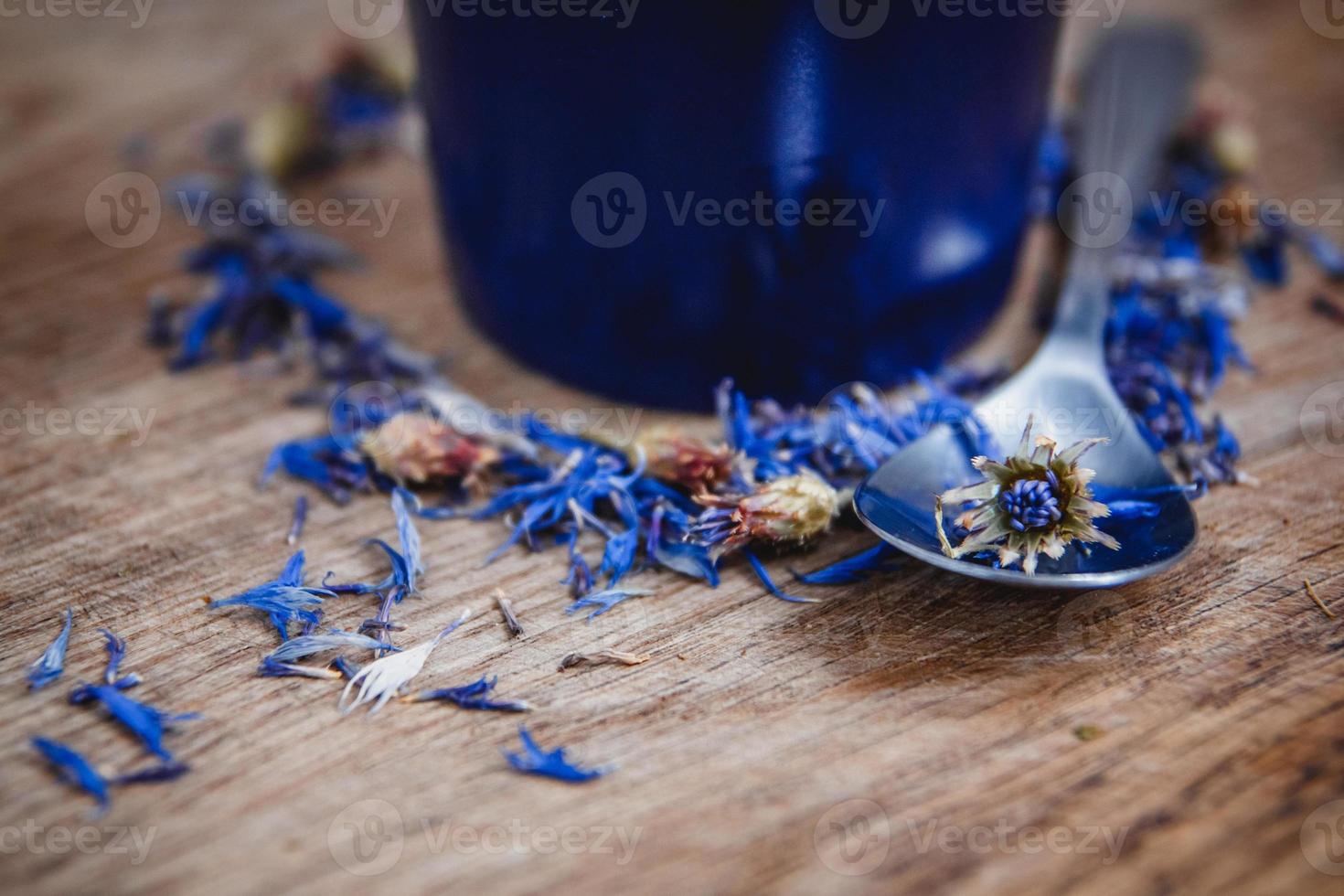 Taza y cuchara azul con té negro de flores sobre un fondo de madera foto