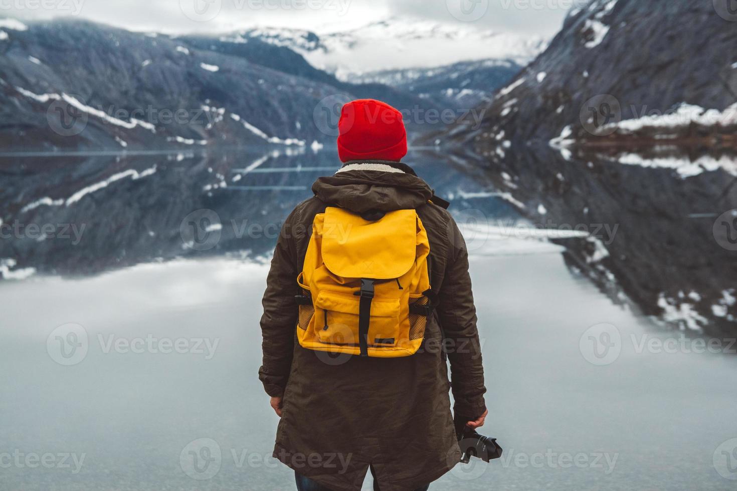 man standing on background of mountains and lake makes a photo