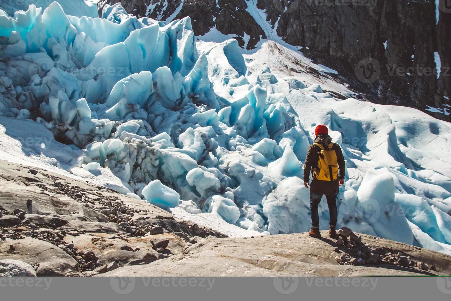 Hombre viajero de pie sobre una roca en el fondo de un glaciar foto