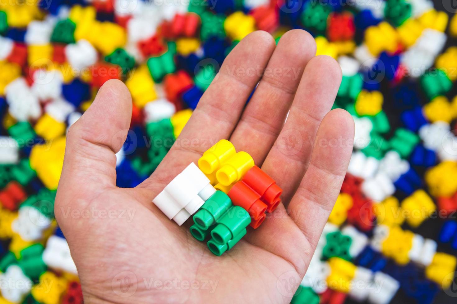 Hand with colorful plastic bricks on a colorful background photo