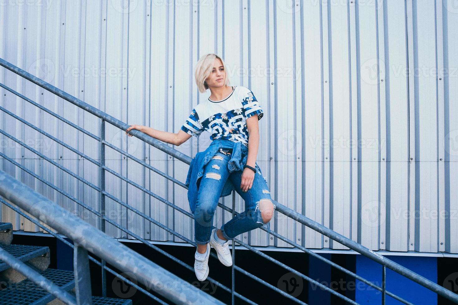 woman with short white hair in urban style sits on the metal stairs photo