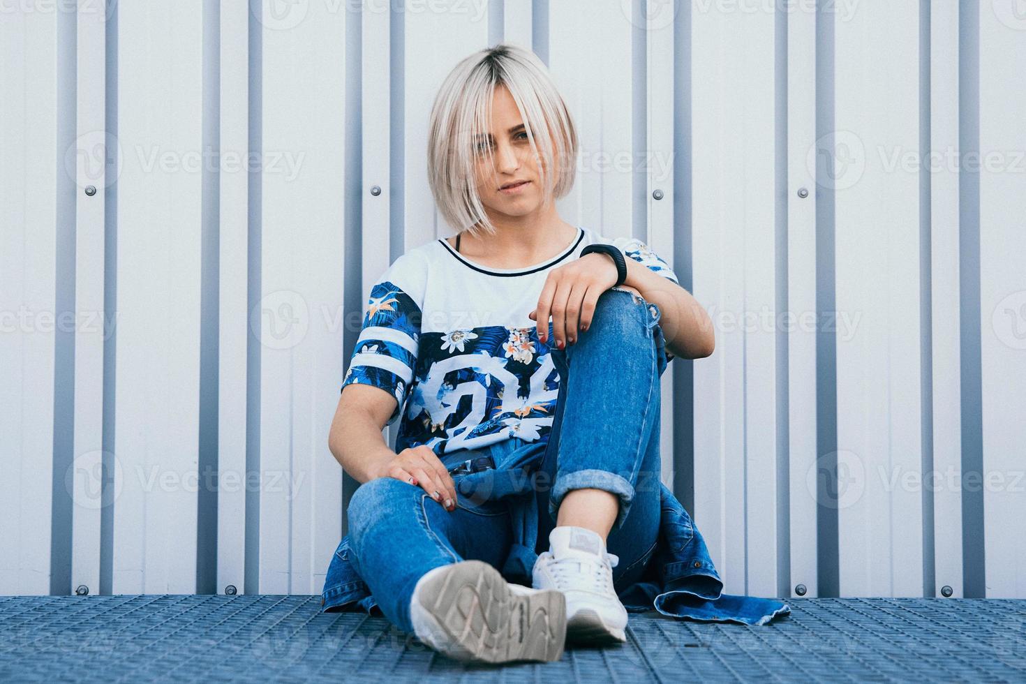 woman with short white hair sits on the background of metal wall photo