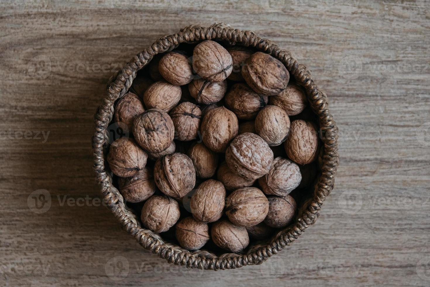 Walnuts in a round wicker basket on a wooden background photo