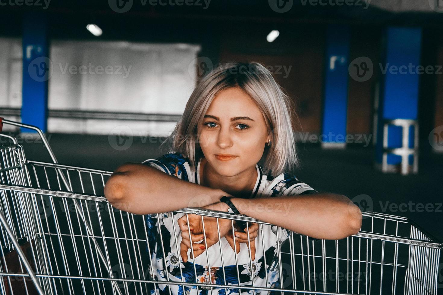 Retrato de mujer vestida con jeans con carritos de compras en el estacionamiento foto