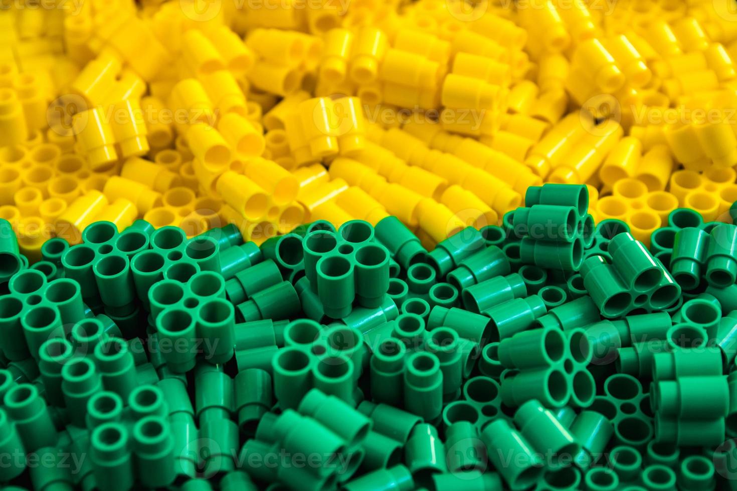 Plastic bricks of yellow and green. Details of toys. Close up. photo