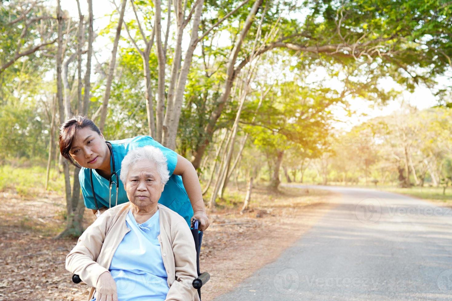 Ayudar y cuidar a una mujer mayor asiática sentada en una silla de ruedas en el parque. foto