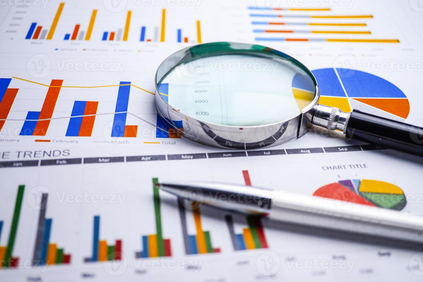 Magnifying glass on charts graphs spreadsheet paper. photo