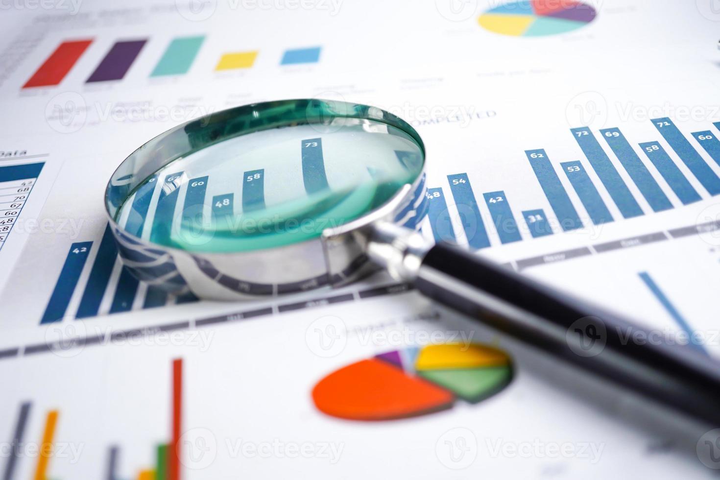 Magnifying glass on charts graphs spreadsheet paper. photo