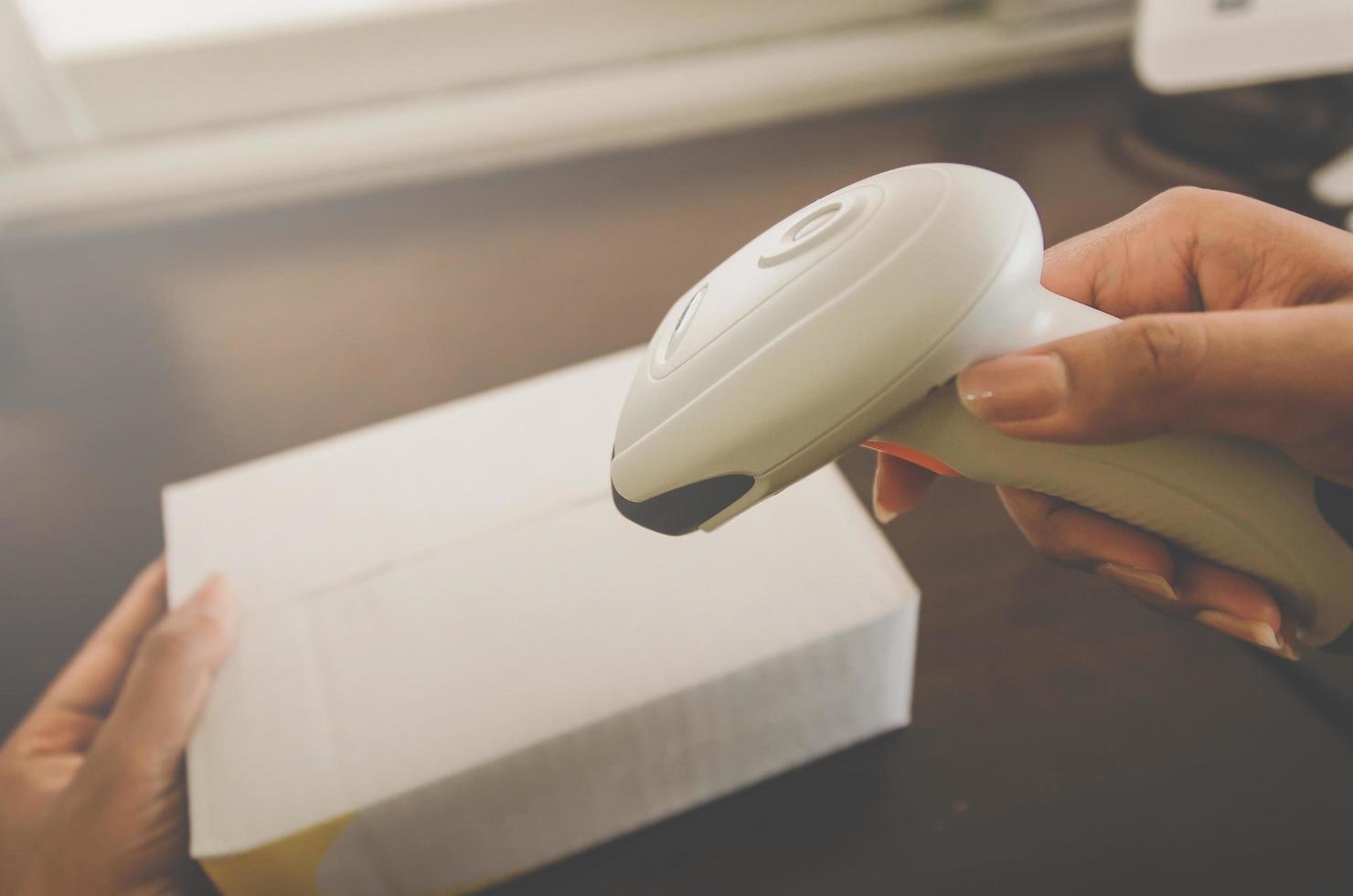 una mano humana sosteniendo un paquete con lector de código de barras para la entrega. foto