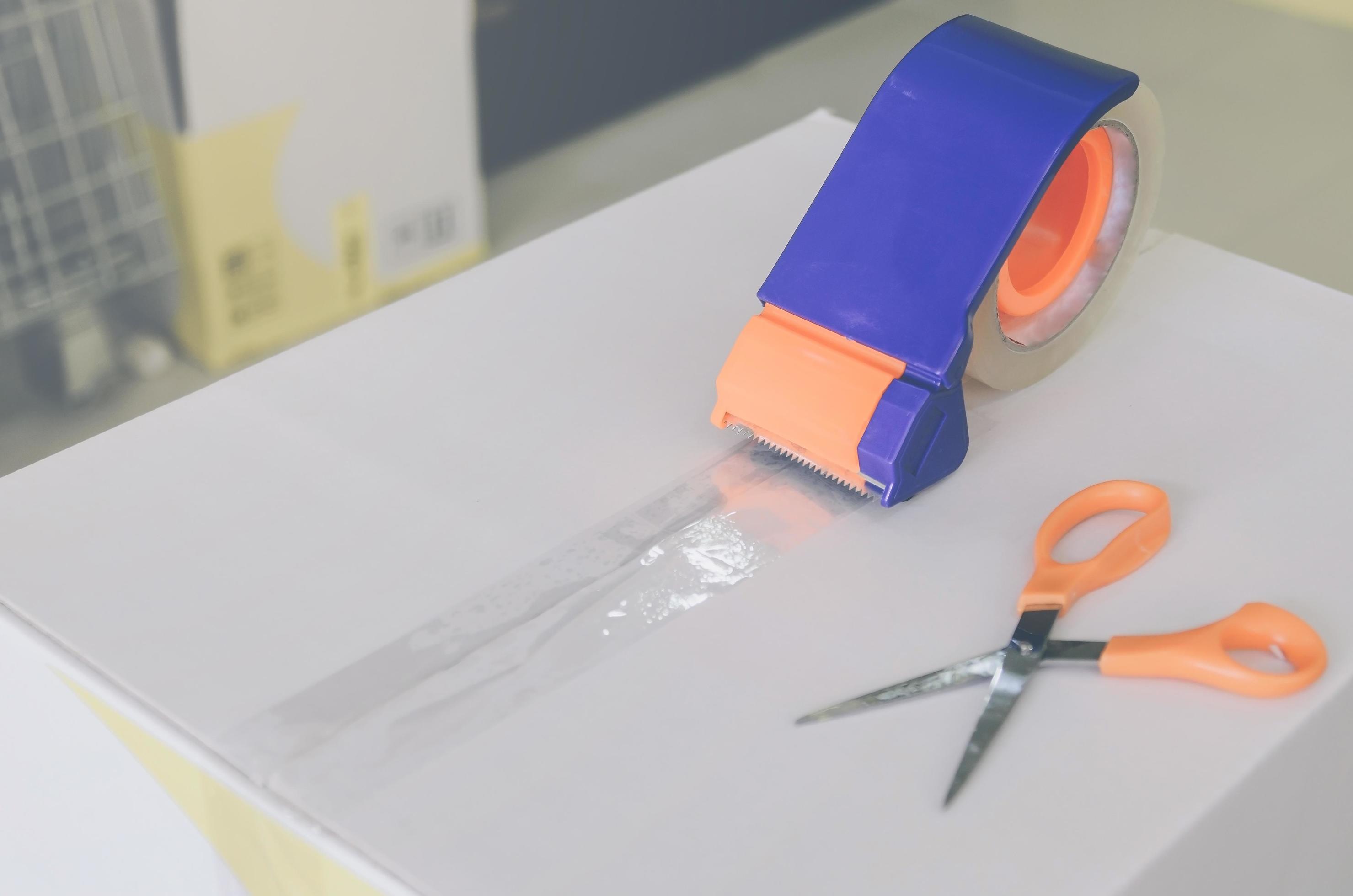 Preparing parcel for shipping with scissors and scotch tape cutter