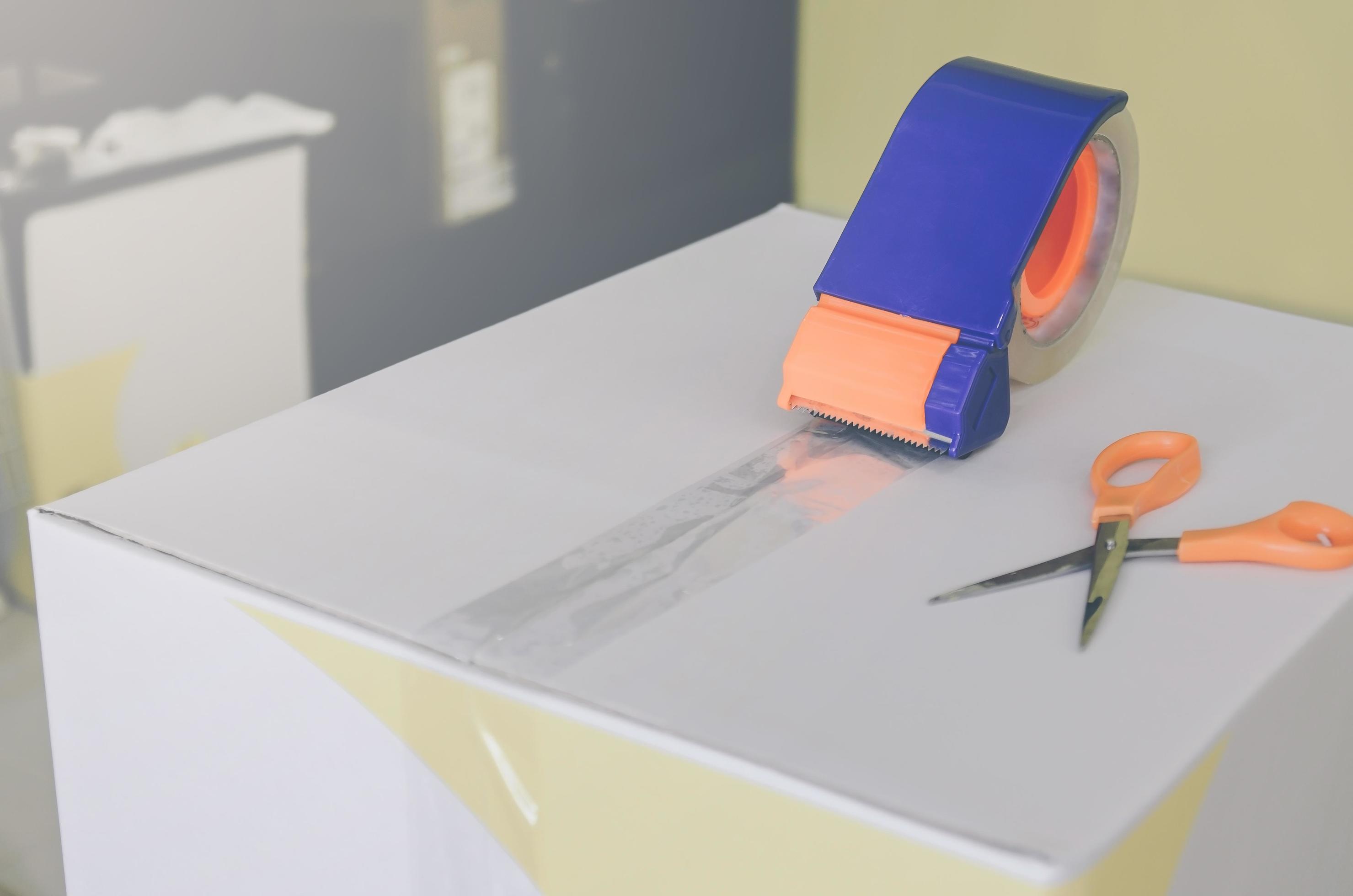 Preparing parcel for shipping with scissors and scotch tape cutter