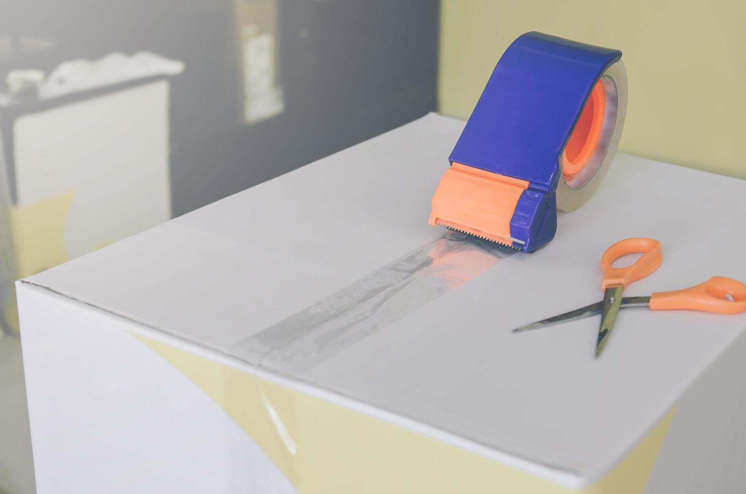 Preparing parcel for shipping with scissors and scotch tape cutter. photo
