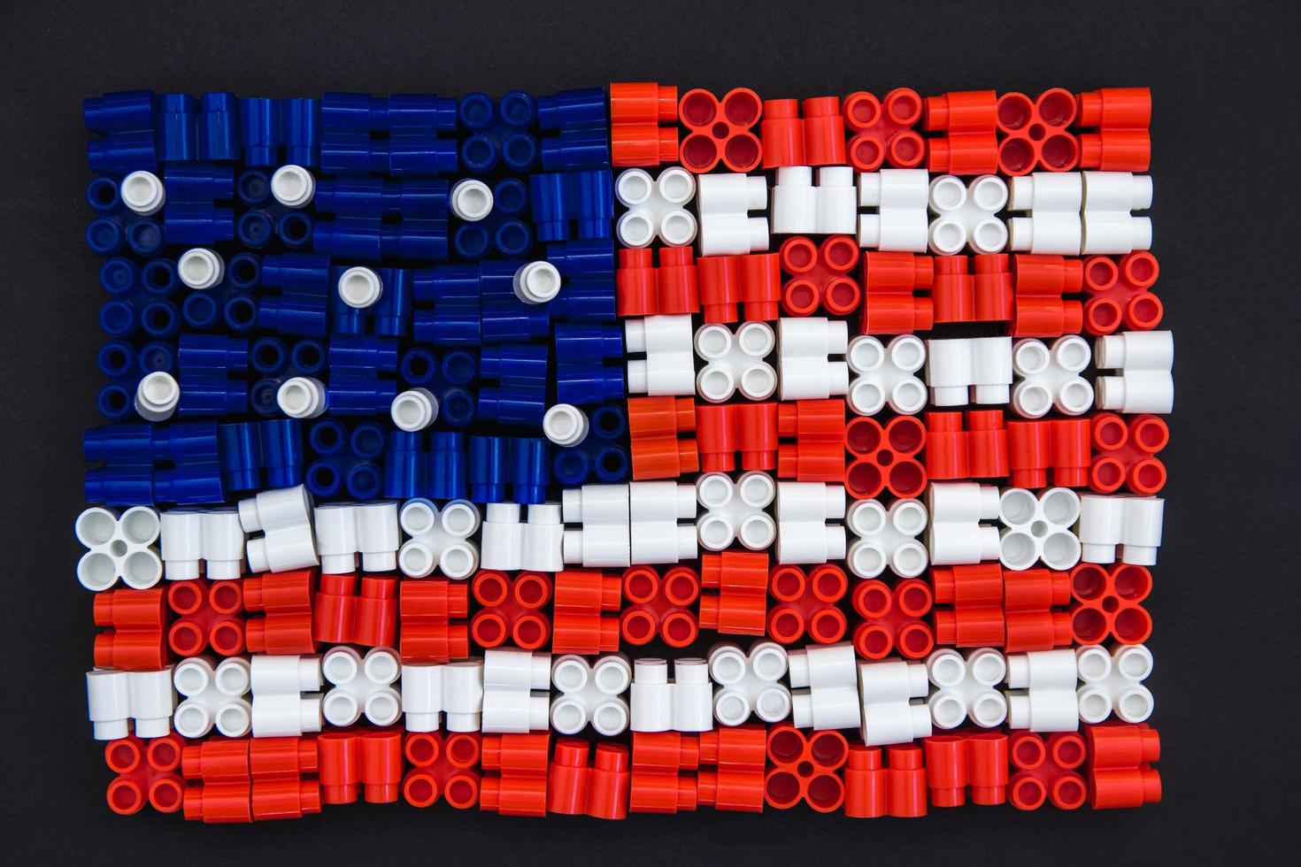 Coloridos ladrillos de plástico que forman la bandera estadounidense sobre fondo negro foto
