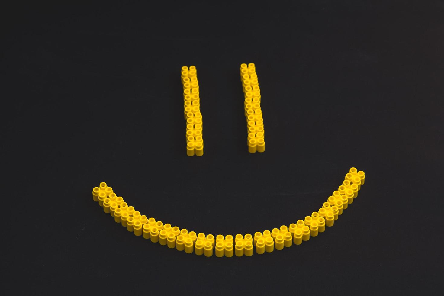 plastic bricks of yellow color, forming a smile on a black background photo