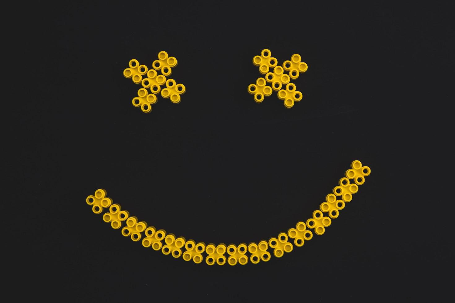 plastic bricks of yellow color, forming a smile on a black background photo