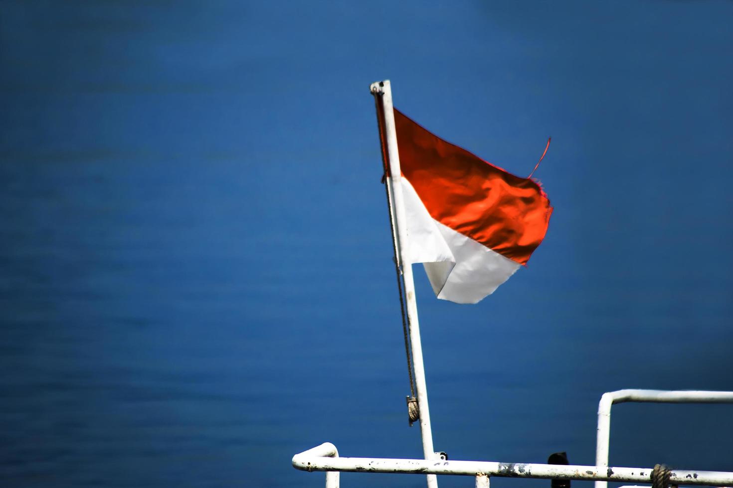 Indonesia National Flag waving at the blue sea photo