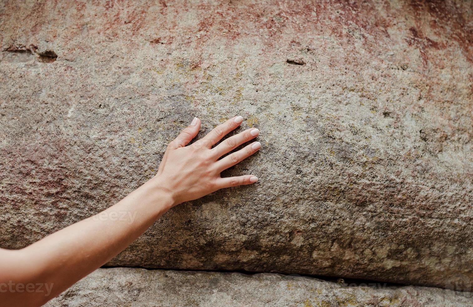 Woman hand touching the rock surface photo