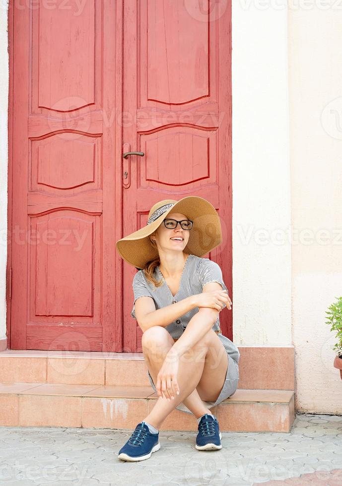 mujer sentada en strairs junto a la puerta roja brillante foto