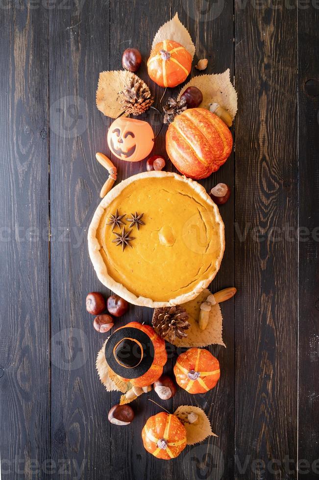 Homemade pumpkin pie with autumn leaves on rustic background, top view photo