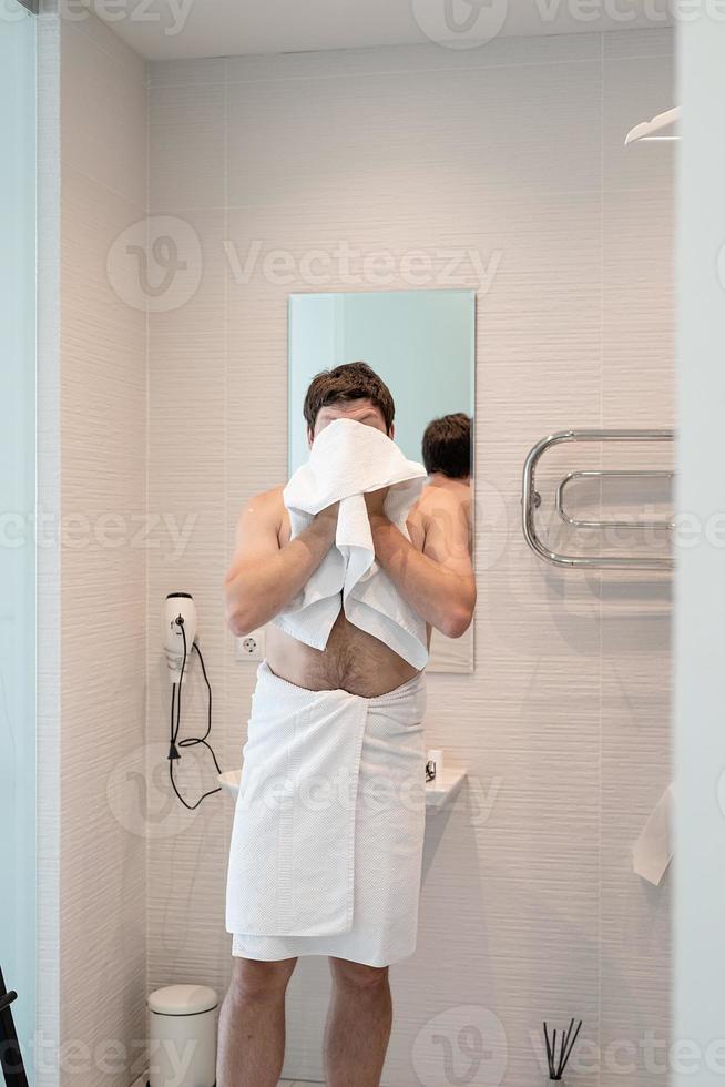 A young man washing his face in the bathroom photo