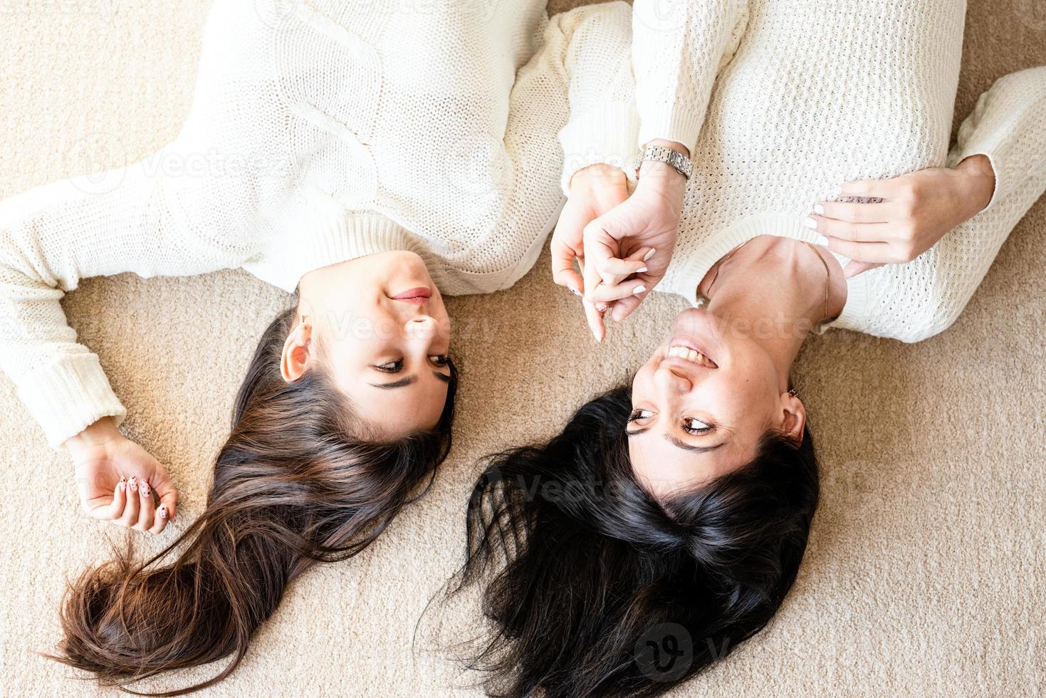 Two best friends laying on the rug at home talking photo