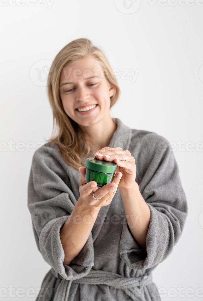 Young woman holding jar with beauty product photo