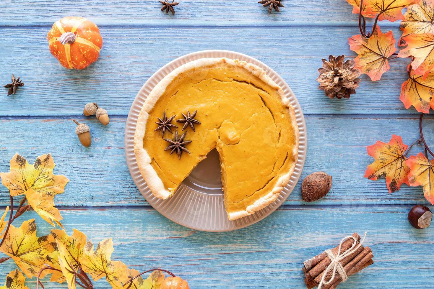 Tarta de calabaza casera con hojas de otoño sobre fondo rústico, vista superior foto