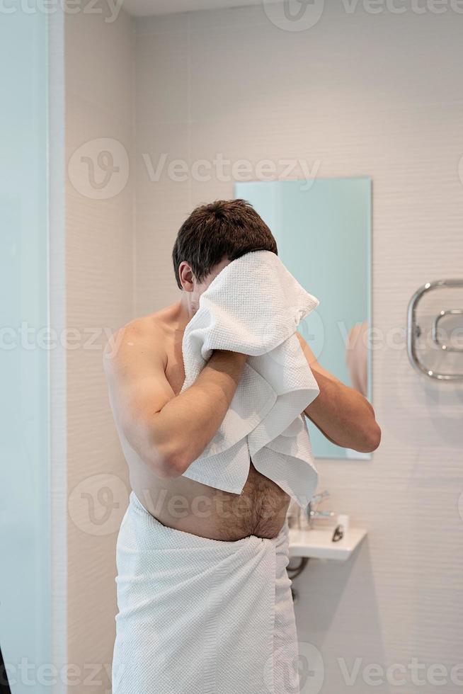 hombre joven cepillándose los dientes en el baño foto