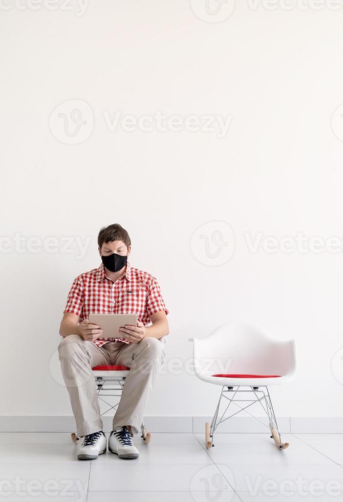 Young man in protective mask studying online keeping social distance photo