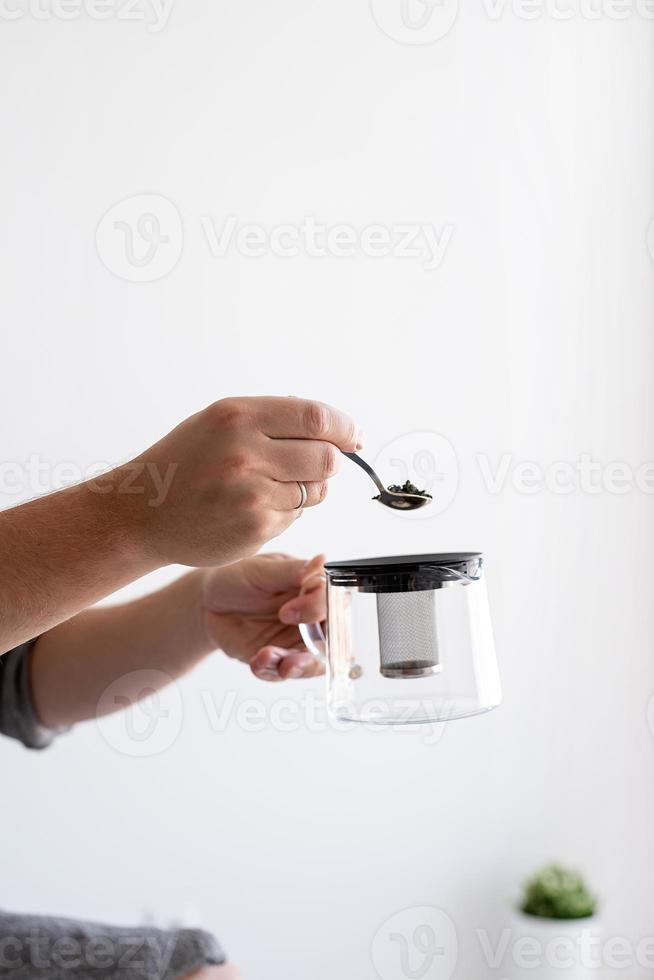 Close up of man hands pouring tea leaves into the teapot photo