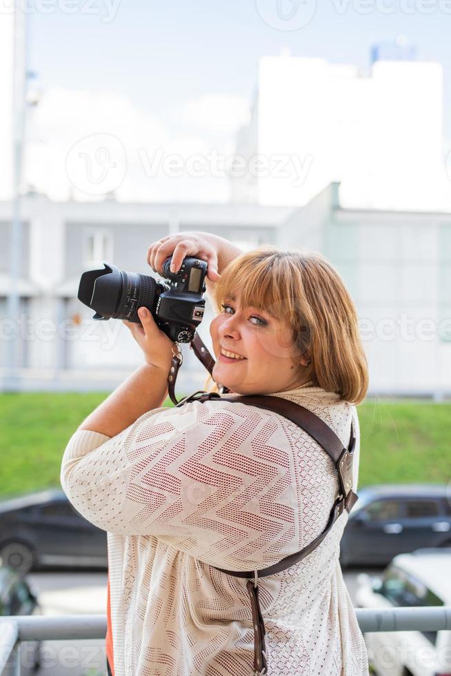 Portrait of overweight woman taking pictures with a camera outdoors photo