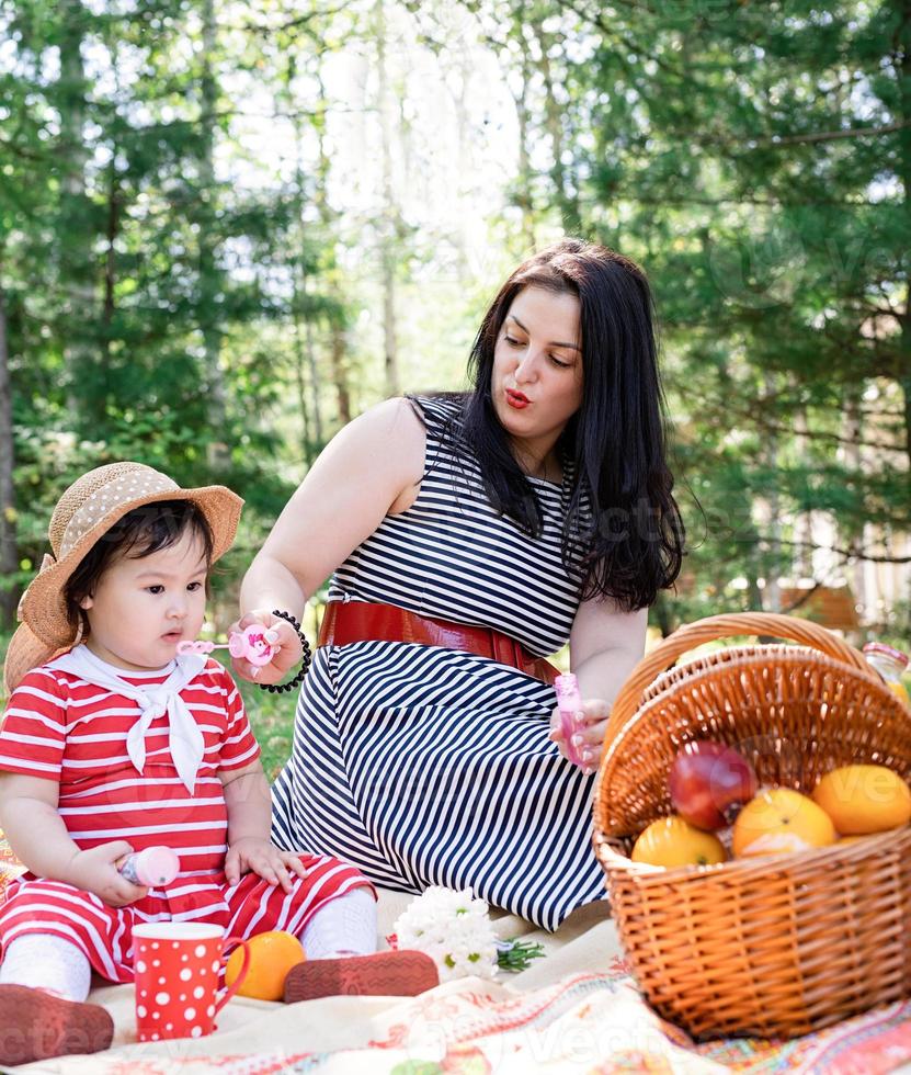 Familia interracial de madre e hija en el parque haciendo un picnic foto