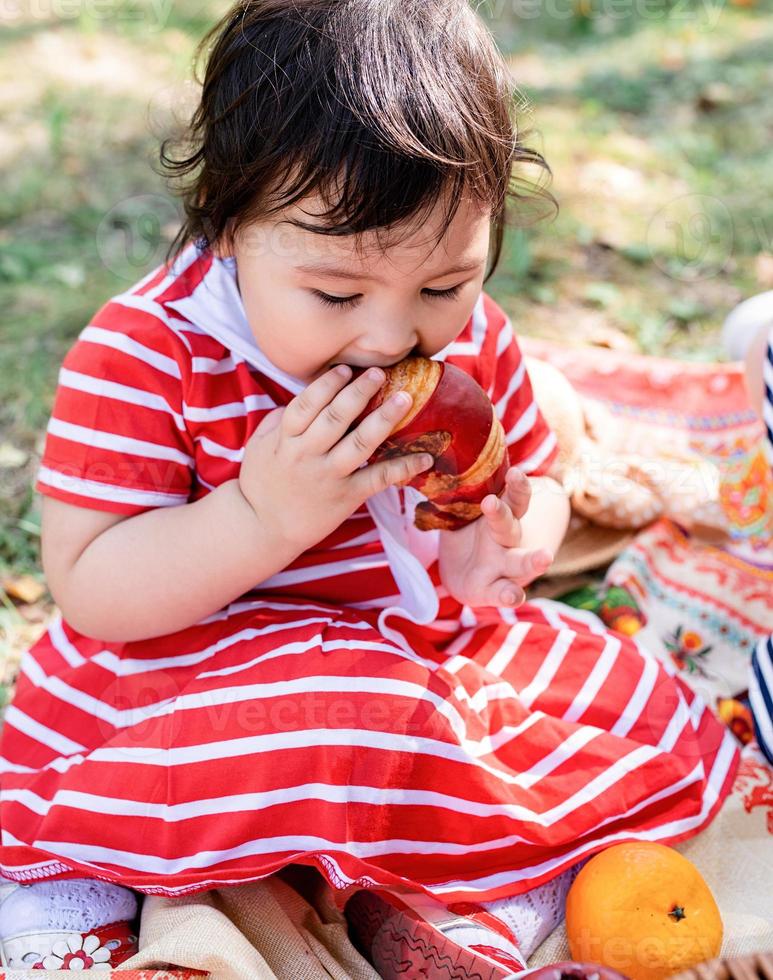 lindo bebé con un vestido rojo y un sombrero srtaw en un picnic en el parque foto