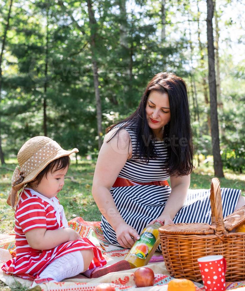 Familia interracial de madre e hija en el parque haciendo un picnic foto