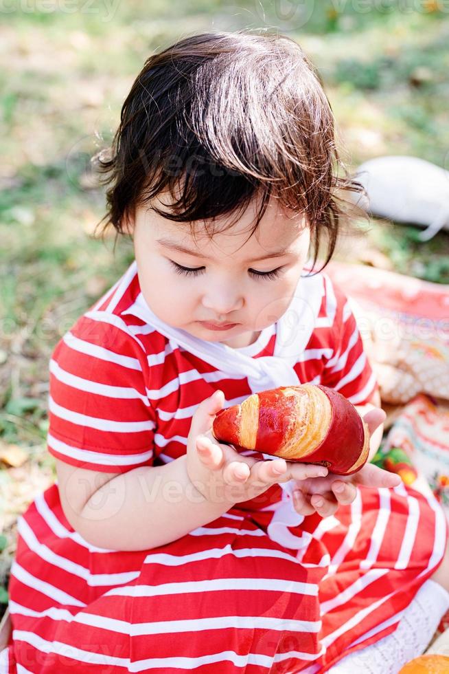 lindo bebé con un vestido rojo y un sombrero srtaw en un picnic en el parque foto