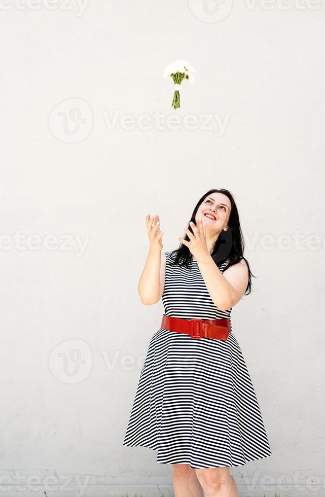 Happy young woman thowing a bouquet of flowers into the air photo