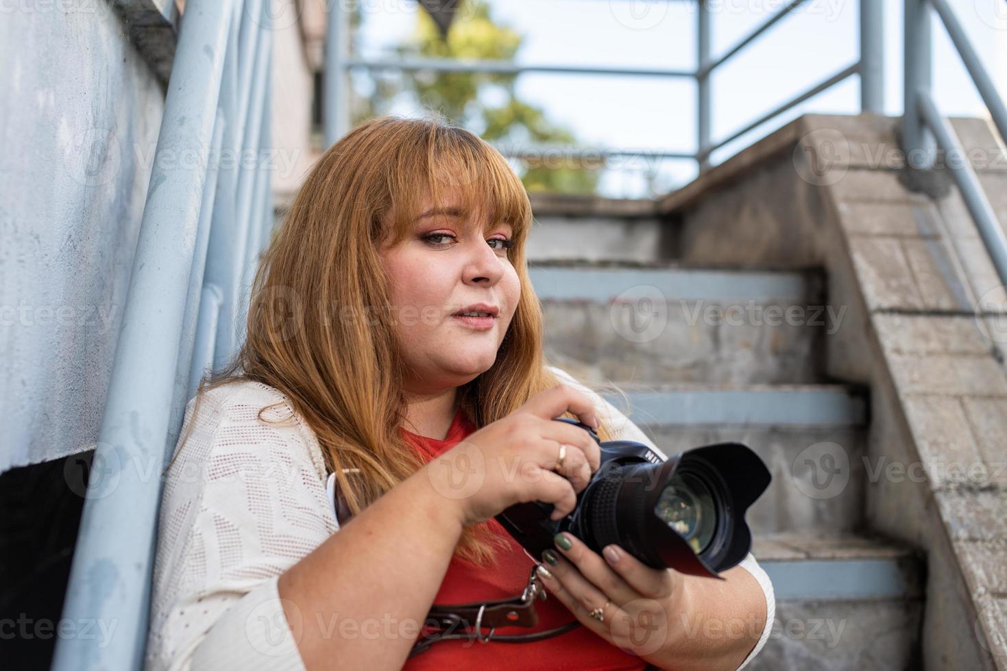 Retrato de mujer con sobrepeso tomando fotografías con una cámara en el exterior foto