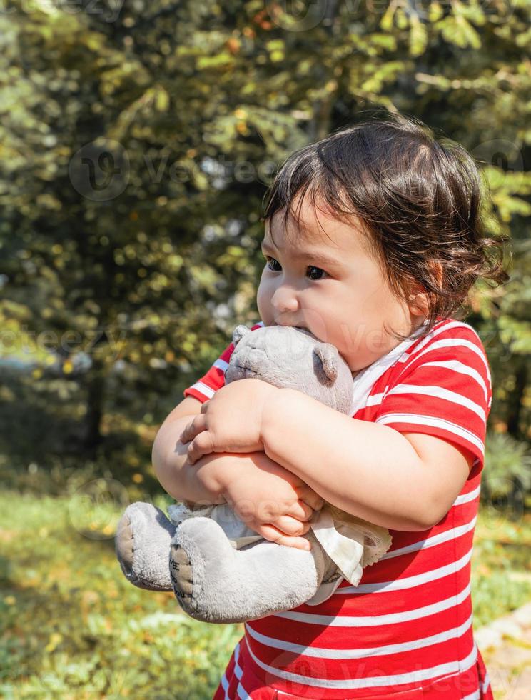 Niña asiática abrazando su juguete caminando al aire libre foto