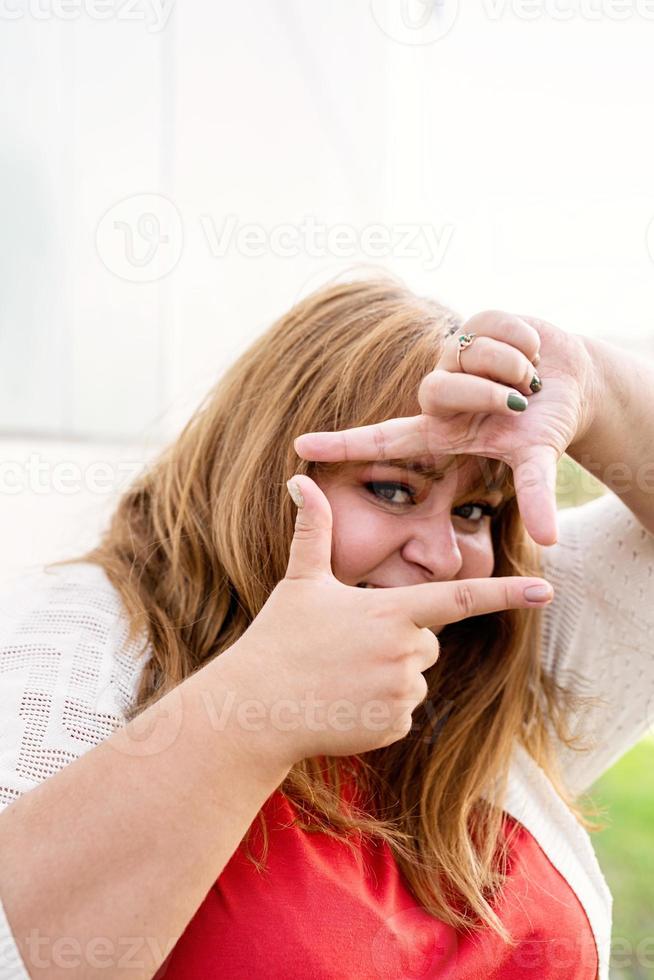 Pretty overweight woman making frame with hands. photo