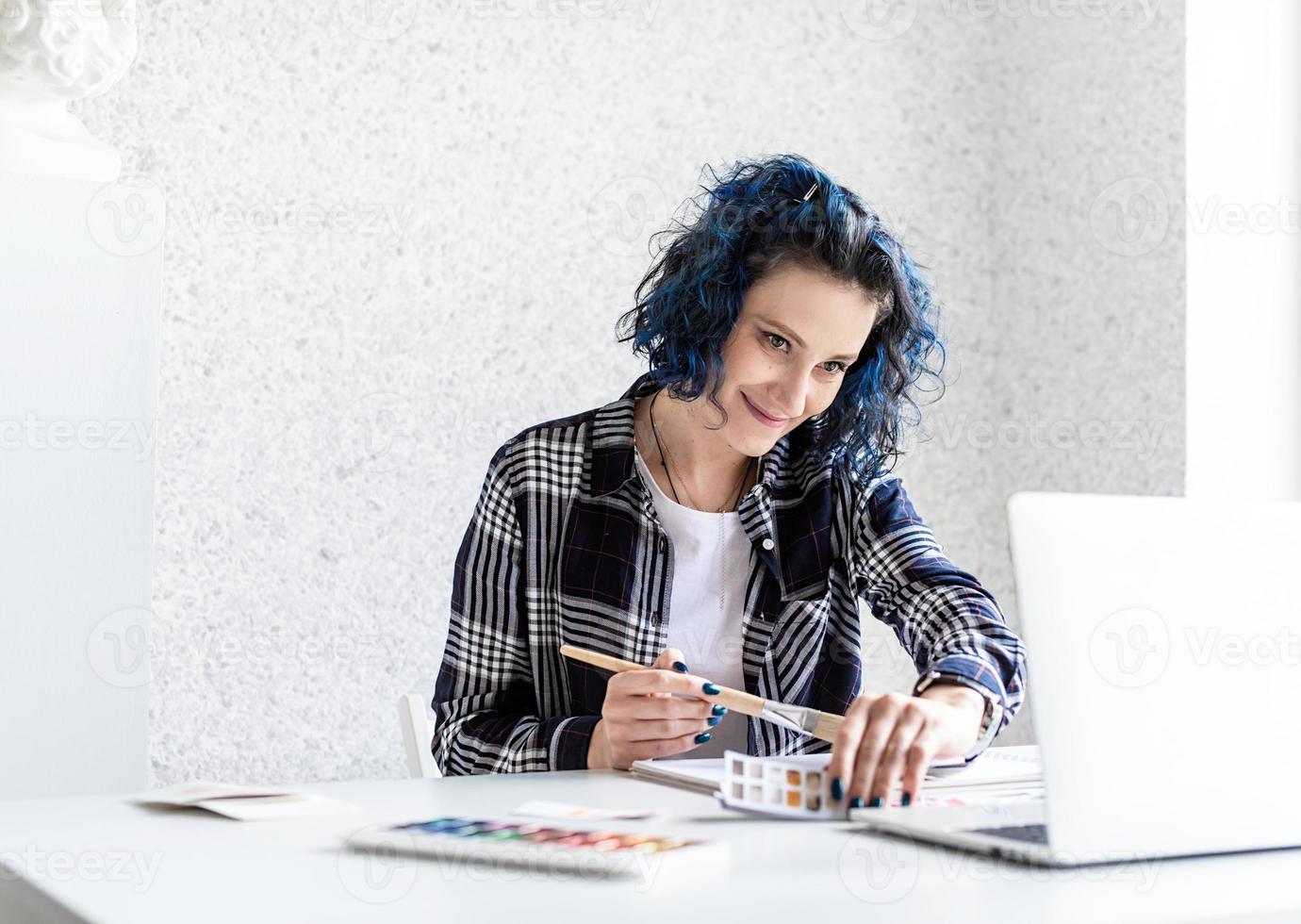 Designer working with colour palettes and laptop in her studio photo