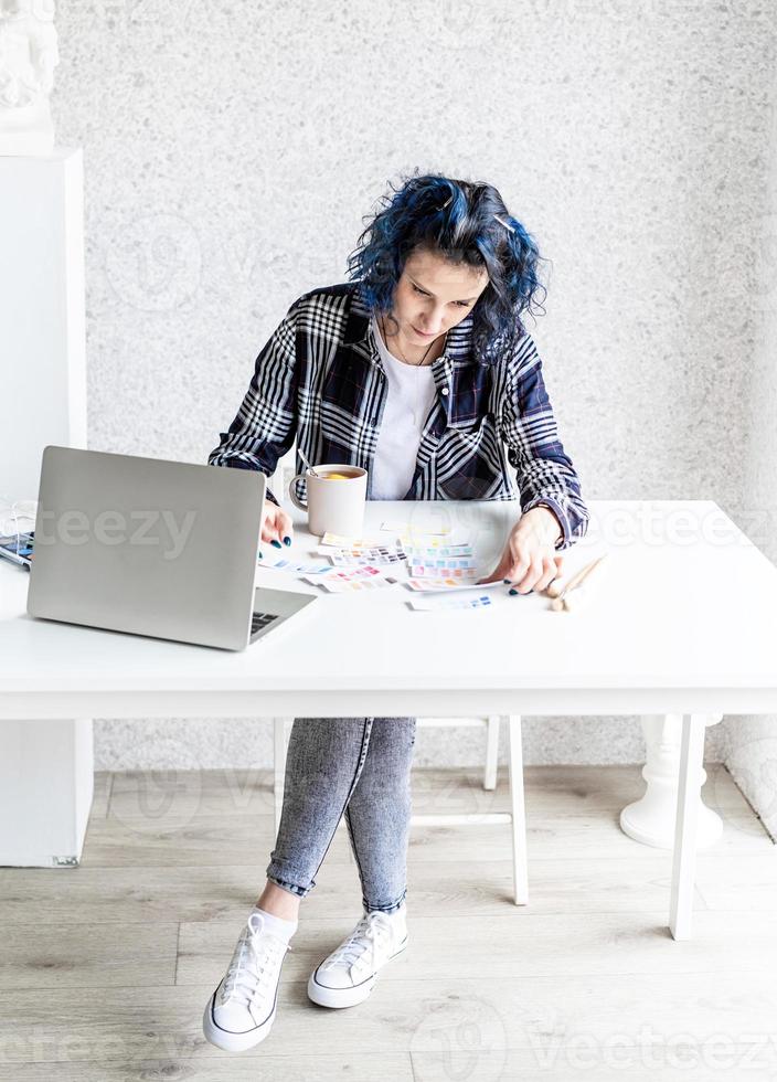 Designer working with colour palettes and laptop in her studio photo